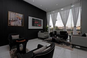 uma sala de estar com cadeiras e uma televisão na parede em وايت مون للأجنحة الفندقية -الرصراص em Khamis Mushayt