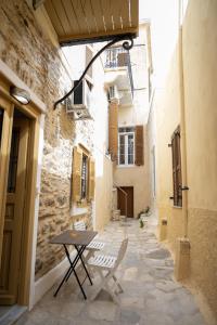 an alley with a table and chairs in an alley at Maya Studio in Ermoupoli