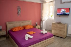 a bedroom with a bed with purple sheets and orange pillows at Maya Studio in Ermoupoli