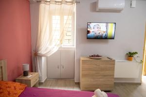 een slaapkamer met een bed en een tv aan de muur bij Maya Studio in Ermoupoli