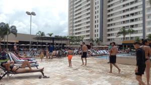 eine Gruppe von Menschen steht um einen Pool in einem Resort herum in der Unterkunft Solar das Águas Park Resort in Olímpia