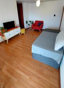 a bedroom with a bed and a tv and a red chair at Espacio C Av Marcelo t de Alvear Vista Centro in Córdoba