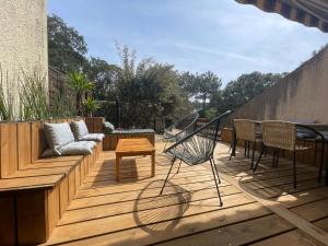 eine Terrasse mit einem Sofa, einem Tisch und Stühlen in der Unterkunft Maison chaleureuse sous les pins in Seignosse
