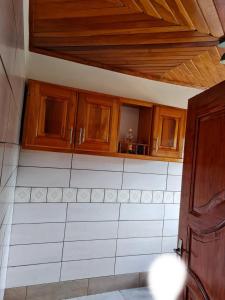 una cocina con armarios de madera y azulejos blancos en ND SMART RESIDENCE en Limbe