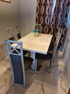 una mesa y sillas en una habitación con cortina en ND SMART RESIDENCE en Limbe