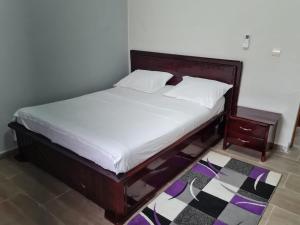 un letto con lenzuola bianche e testiera in legno di ND SMART RESIDENCE a Limbe