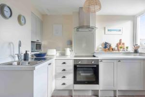 La cuisine blanche est équipée d'un évier et d'un four. dans l'établissement The Little Loft St Ives, à St Ives 31 autres photos