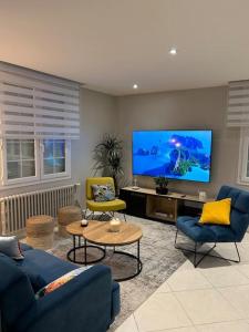 sala de estar con sofá azul y TV de pantalla plana en Maison familiale face à la mer, en Regnéville-sur-Mer