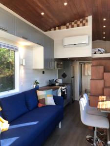 Modern Private Tiny House in the Forest في Slocan: غرفة معيشة مع أريكة زرقاء في منزل صغير