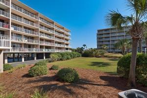 a large apartment building with a palm tree and a yard at Beachfront - Renovated - Gulf view Bedroom - FLPCB5 in Panama City Beach