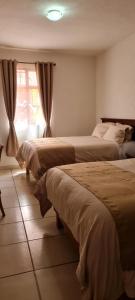 a bedroom with two beds and a window at Hotel El Beso De Calixto in Guanajuato