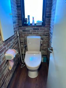 a bathroom with a white toilet in a brick wall at ゲストハウス れんげ苑 in Shimosato