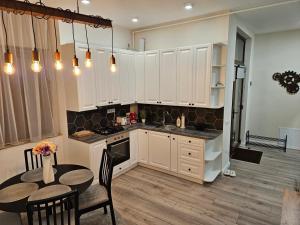 a kitchen with white cabinets and a table with chairs at Cozy apartament in Sighetu Marmaţiei +7 photos