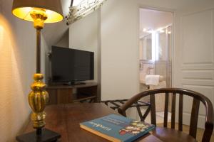 a table with a book and a lamp and a tv at Aux Charmes de Maintenon in Maintenon