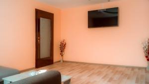 sala de estar con sofá y TV en la pared en Little Star Apartment, en Oradea