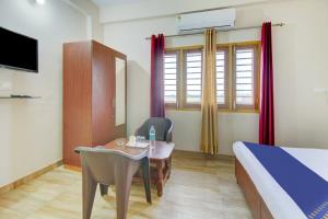 una camera d'albergo con letto, scrivania e tavolo di SPOT ON Chandra's Residence a Dehradun