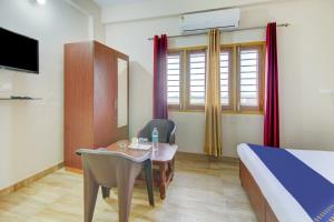 a hotel room with a bed and a desk and a table at SPOT ON Chandra's Residence in Dehradun