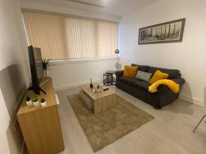 a living room with a black couch and yellow pillows at Luxury 2 Bedroom Charter House in Milton Keynes