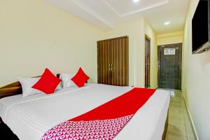 a bedroom with a large white bed with red pillows at OYO Adhin Residency in Hyderabad
