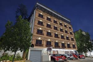 海得拉巴Townhouse OAK Hotel Belsons Taj Mahal的一座高楼，前面停着汽车