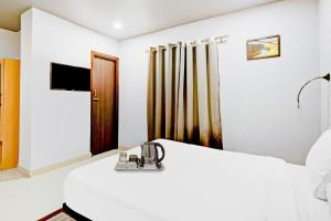 ein weißes Zimmer mit einem Bett und einem Spiegel in der Unterkunft Super Townhouse 406 Volga Homes in Kāhārpāra
