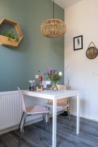 une table blanche avec deux chaises et un vase de fleurs dans l'établissement @ geulle, à Guelle