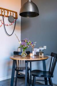 une table à manger avec des chaises et un vase de fleurs dans l'établissement @ geulle, à Guelle