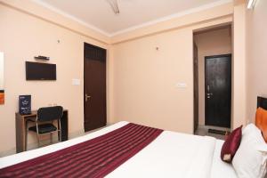 Schlafzimmer mit einem Bett, einem Schreibtisch und einem TV in der Unterkunft OYO Rn 32 in Indirapuram