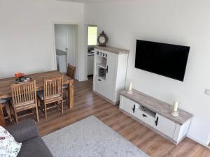 a living room with a television and a dining room at Ferienhaus 2-6 Pers Europa Feriendorf neu renoviert mit Sauna in Husen