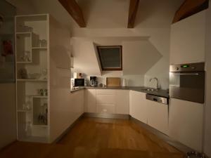 a kitchen with white cabinets and a wooden floor at Apartment Bujrum & Enjoy in Sarajevo