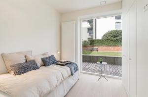 Habitación blanca con sofá y ventana grande. en Zoute - Lovely ground floor app., en Knokke-Heist