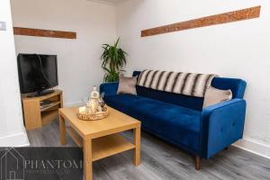 ein blaues Sofa im Wohnzimmer mit einem Tisch in der Unterkunft Complex Suite in Glasgow