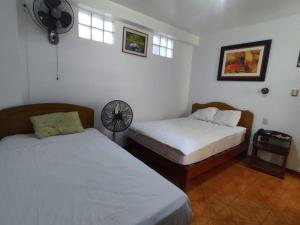 Hotel San Isidro في تروخيو: غرفة نوم بسريرين ومروحة