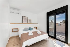 Dormitorio blanco con cama y ventana grande en Casa del puerto, encanto junto al mar, en Estepona