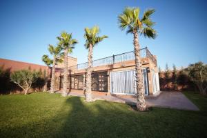 ein großes Haus mit Palmen im Hof in der Unterkunft Luxury Villa écologique in Agadir