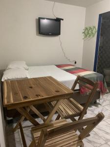 drewniany stół i łóżko z telewizorem na ścianie w obiekcie Pousada Maceio Praia w mieście Maceió
