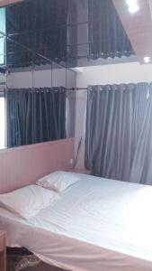 sypialnia z białym łóżkiem i szarymi zasłonami w obiekcie Skyview Setiabudi Apartment w mieście Sunggal