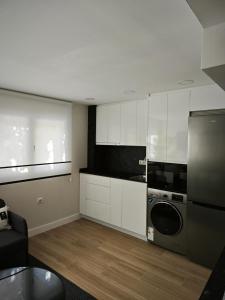 Una cocina con gabinetes blancos y lavadora y secadora. en Studio Sevilla Suites Málaga, en Málaga