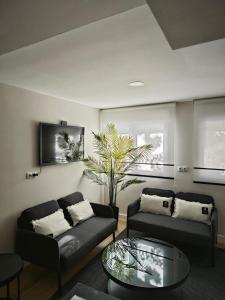Una sala de estar con dos sofás y una palmera. en Studio Sevilla Suites Málaga, en Málaga