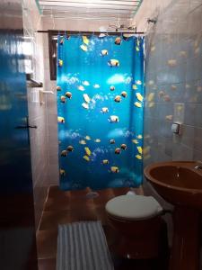 a bathroom with a blue shower curtain with a toilet at Pousada Chalés Vereda do Sol in Ubatuba +39 photos