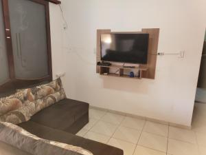 een woonkamer met een bank en een tv aan de muur bij Casa de praia Jequitiba, 50 metros do mar com piscina!!ITANHAÉM! in Itanhaém