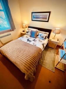a bedroom with a large bed with a blanket on it at Grey Stag Apartment in Nairn