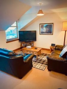 a living room with two couches and a flat screen tv at Grey Stag Apartment in Nairn