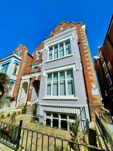 a tall white building with a black fence at Sea Breeze Apartments in Bournemouth