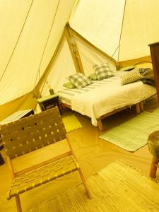 um quarto com uma cama e uma cadeira numa tenda em Glamping Bed and Breakfast Finca Alegria de la Vida em Pizarra