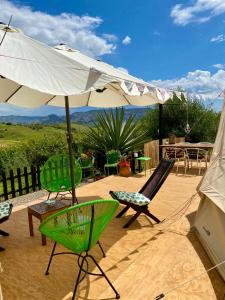 a patio with chairs and an umbrella and a table at Glamping Bed and Breakfast Finca Alegria de la Vida in Pizarra