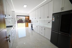 a kitchen with white cabinets and a black refrigerator at Villa Écologique à Proximité de la Plage in Agadir