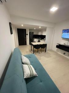a living room with a blue couch and a kitchen at Nuevo Departamento de categoría de 2 ambientes con cochera y amenities premium en ROYAL PARK Mar del Plata, excelente ubicación a dos cuadras de la playa, para 4 PAX in Mar del Plata
