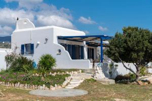 Una casa blanca con un árbol delante. en Cycladic home in Paros, en Kampos