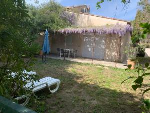 un jardín con mesa y glicinias púrpuras en Les jonquiers, gîte indépendant cosy avec jardin, en Aubagne